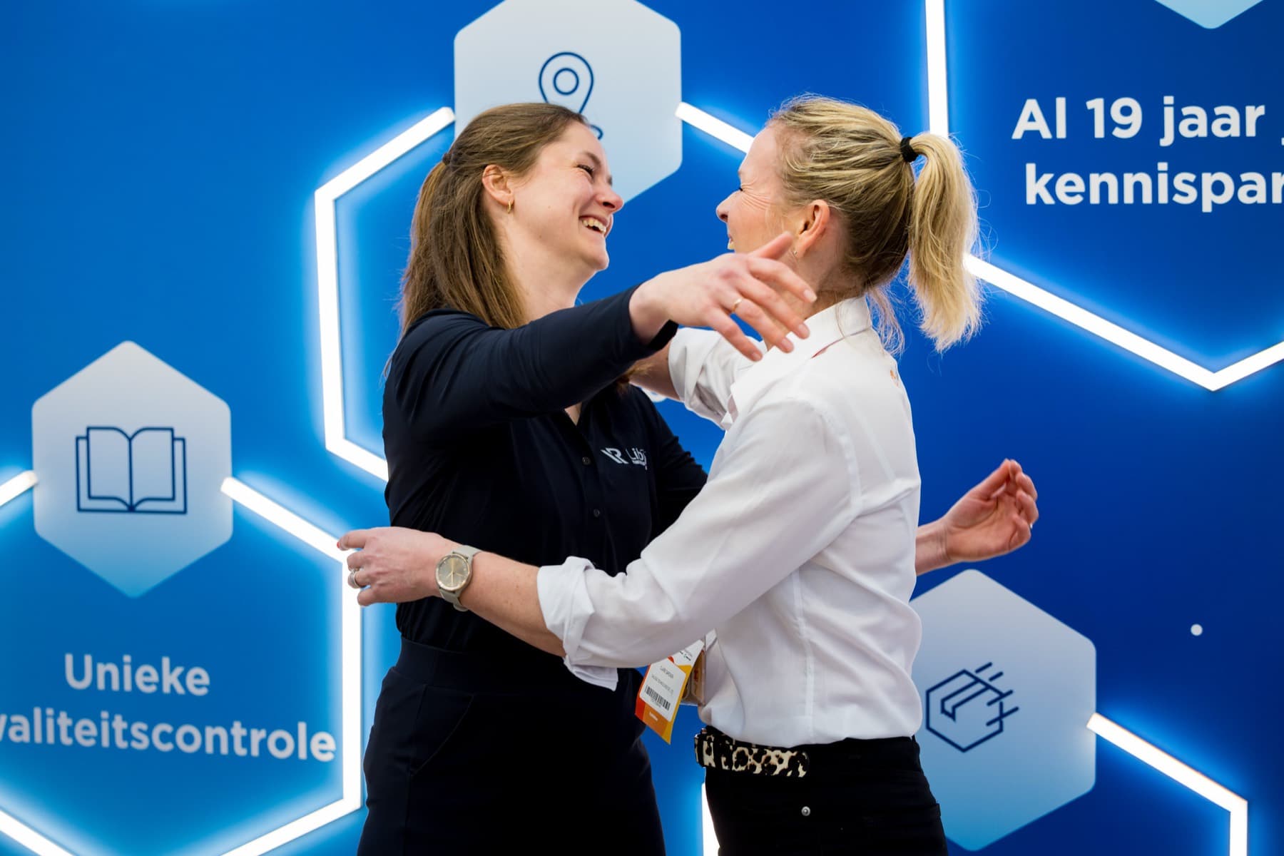 Warm weerzien tussen twee professionals voor een blauwe branded beurswand