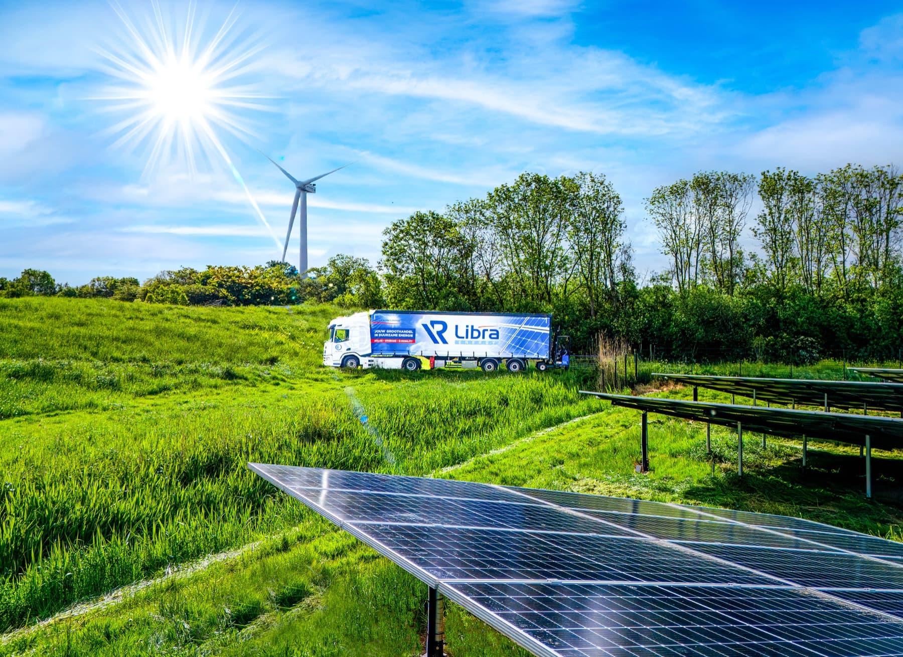 Campagnebeeld met zonnepanelen, windmolen en vrachtwagen in fel zonlicht
